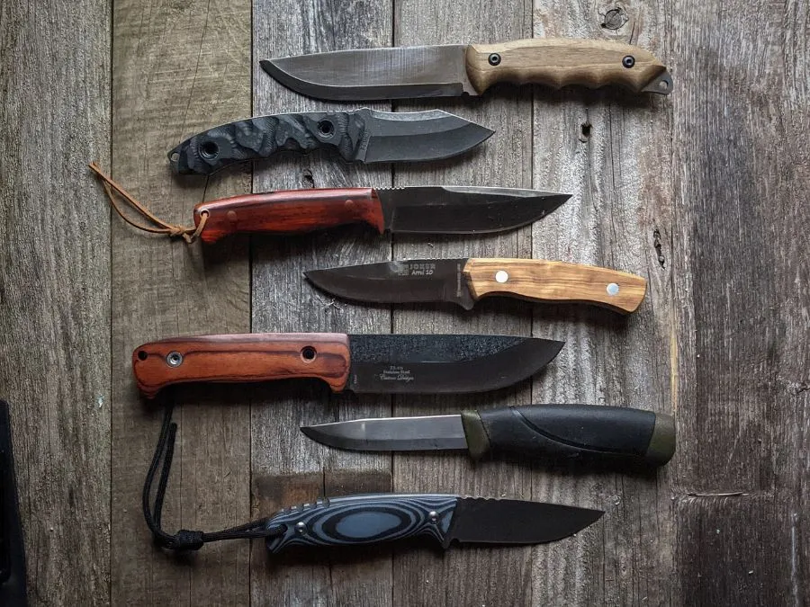 A  set of 7 Best Bushcraft Knives is displayed on a rustic wooden surface, showcasing a variety of handle materials and blade designs.