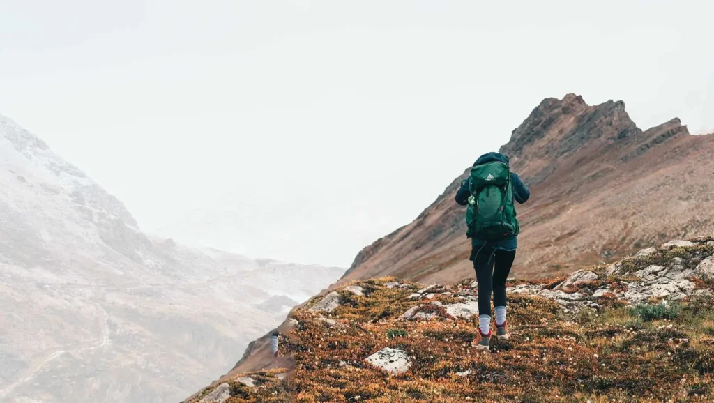 Hiker climbing a mountain trail equipped with the best hiking gear
