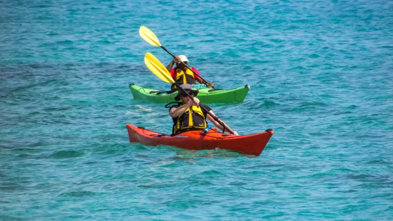 Two people paddling on the ocean in bright-colored kayaks, showcasing the stability and fun of the best inflatable kayak for outdoor adventures.