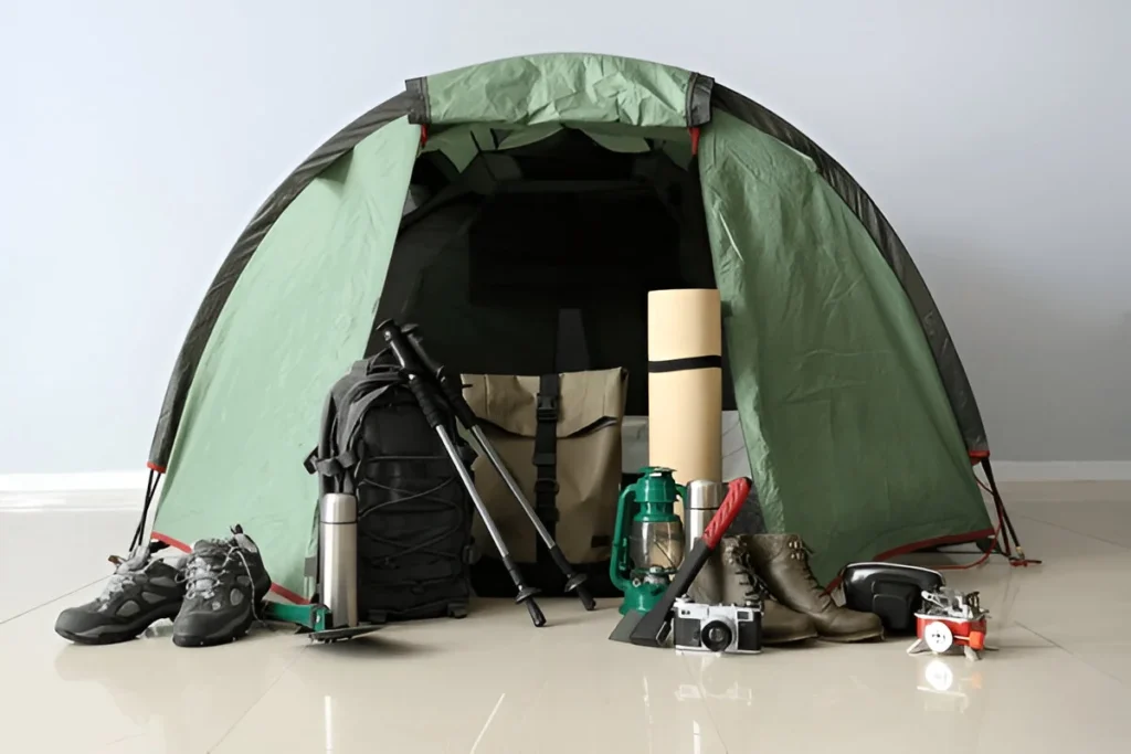 Camping gear display for What to Bring on a Hiking Trip, featuring a tent, backpack, hiking boots, trekking poles, and essential tools.
