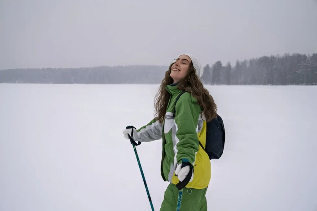 Smiling woman skiing through a snowy forest wearing one of the Best Ski Jackets for Women.
