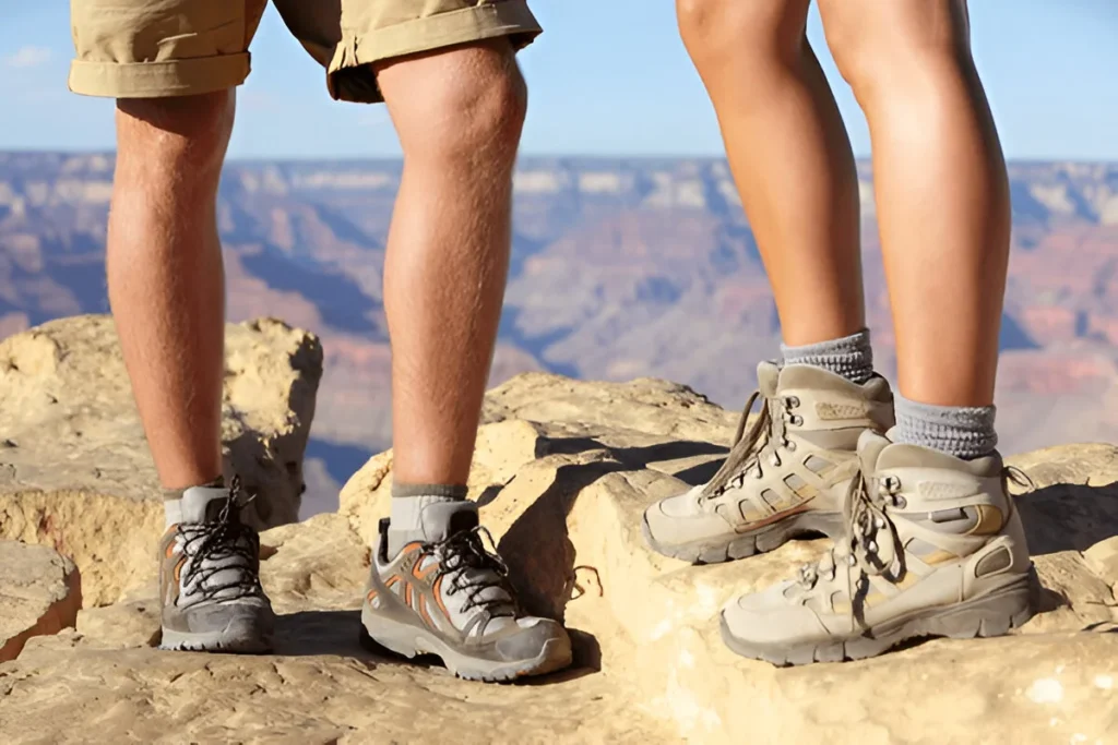 Two hikers stand on a rocky cliff edge wearing durable boots, highlighting the Best Hiking Shoes For Men for rugged terrain.
