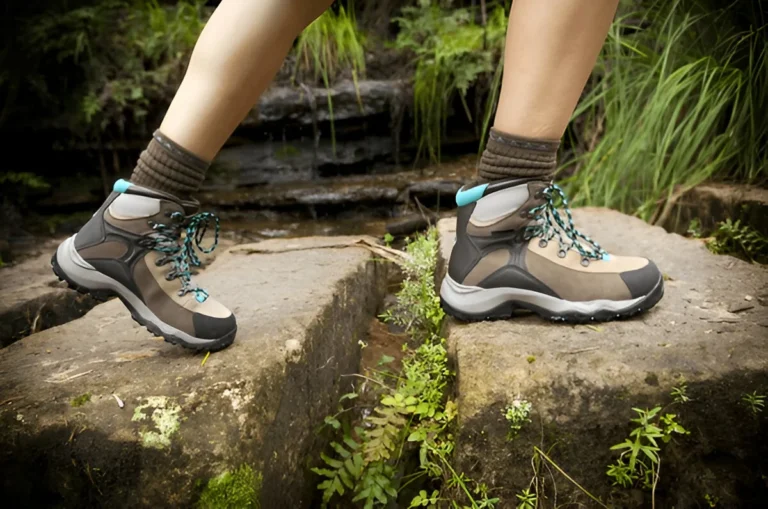 Choose Hiking Shoes for Women: A close-up of a woman wearing sturdy hiking boots while crossing stone steps in a lush outdoor setting.