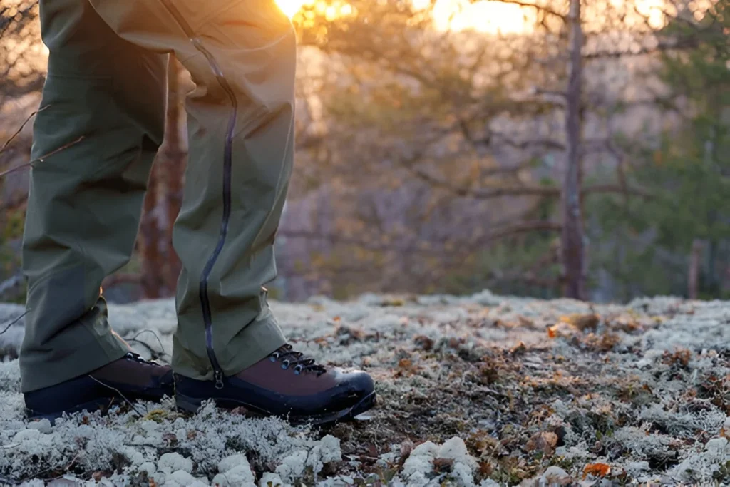 A man walks in a spring forest at sunset. Membrane hiking pants and trekking boots 