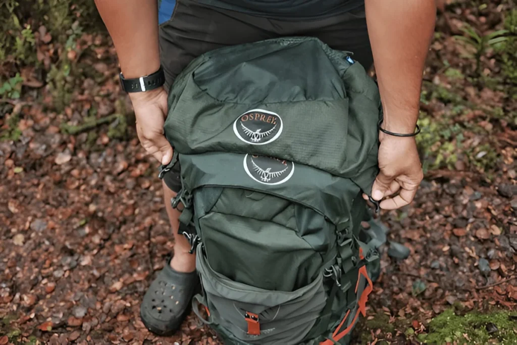 HIKING MAN PACKING & TYING HIS OSPREY BACKPACK DURING OUTDOOR HIKING SESSION CONCEPT