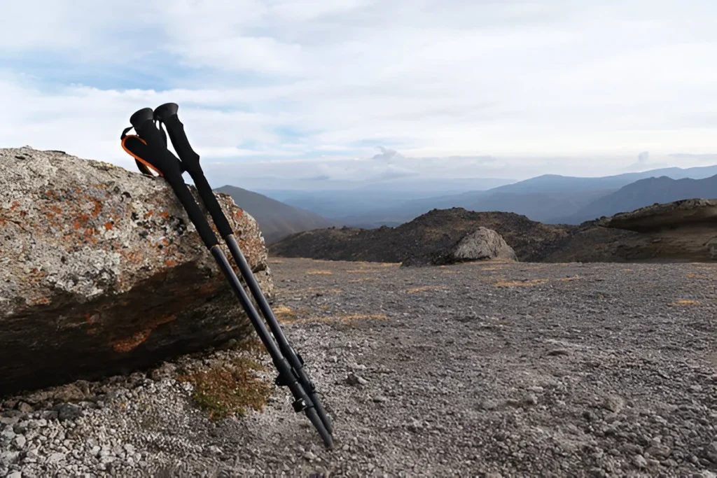Professional sticks for climbing a mountain near a stone on a high mountain path against a blue sky and white clouds