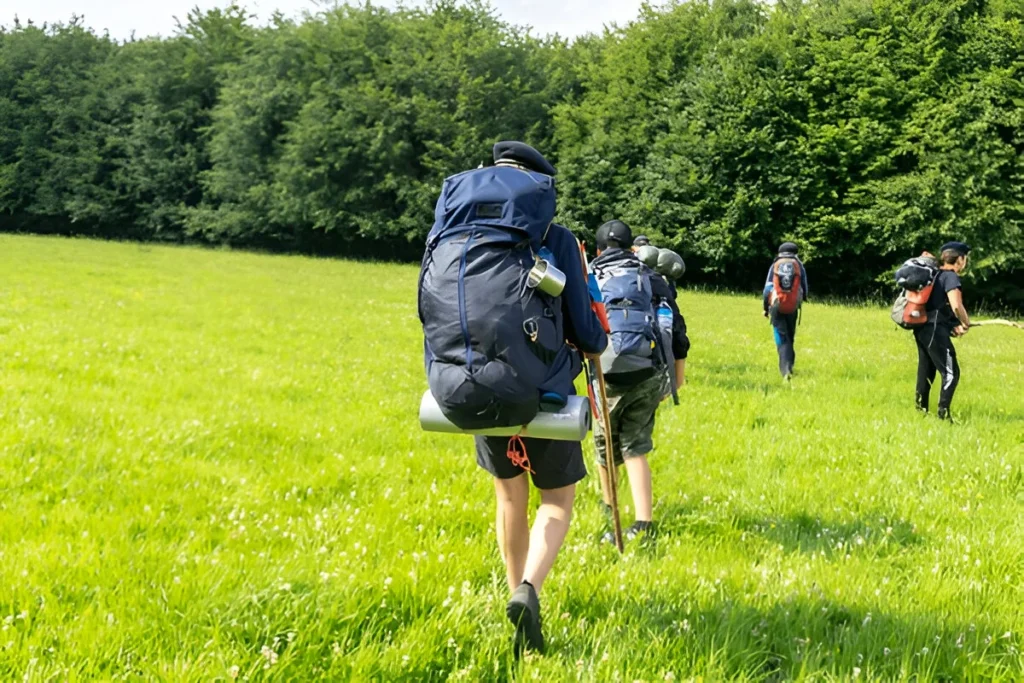 Scouts or tourists go with big hiking backpacks on the green forest trail on sunny summer day