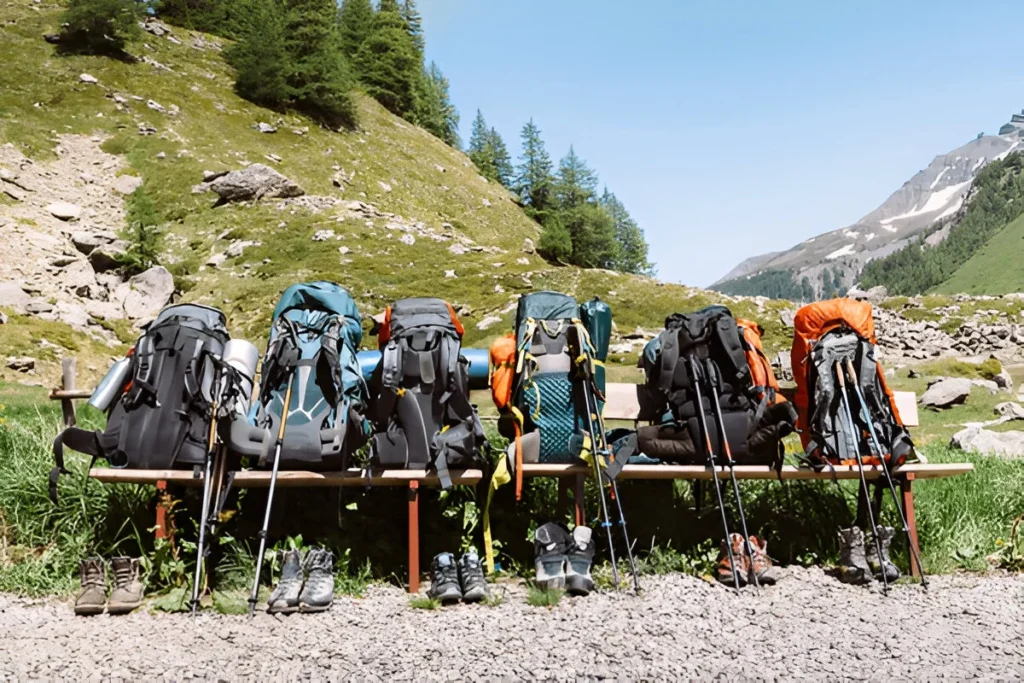 Travel backpacks with sticks and boots for hiking in the mountains while tourists rest from backpacking