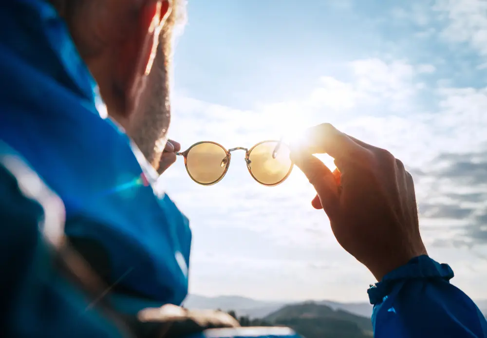 Backpacker man looking at bright sun through polarized sunglasses