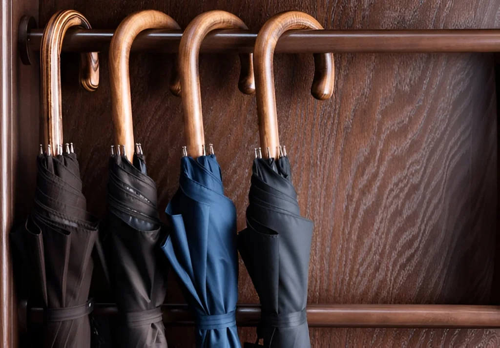 Different classic wooden handle walking length umbrellas on display in luxury clothing boutique store