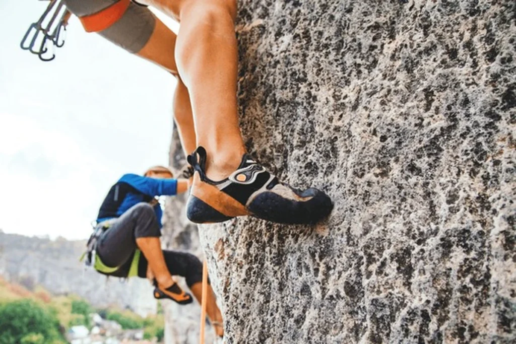 "Two climbers scaling a rocky wall while wearing some of the best climbing shoes designed for grip and precision."