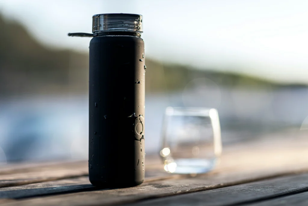 A sleek black insulated bottle sitting on a wooden surface with water droplets, perfect for those searching for the Best Water Bottles.